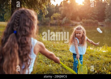 Badminton. Kleines Mädchen spielt Badminton mit Schwester im Frühlingspark. Kinder haben Spaß im Freien. Spiele im Freien Stockfoto