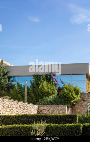 Eine Fassade eines Gebäudes mit Fenstern, die den blauen Himmel an einem sonnigen Tag im Sommer reflektieren. Moderne Architektur, minimalistischer Stil. Wunderschöne Buttelrfly BU Stockfoto