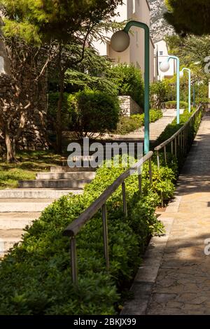 Bol, Kroatien, 10. September 2019. Treppen mit Bäumen und Grün in der Nähe des Boulevards auf der Insel Brac in Dalmatien. Moderne Laternen neben dem Weg. Rel Stockfoto