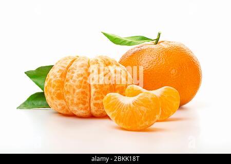 Isolierte Mandarinen. Hälfte der geschälten Mandarinen und ganze Mandarinen- oder Orangenfrucht mit grünen Blättern isoliert auf weißem Grund. Nahaufnahme. Stockfoto