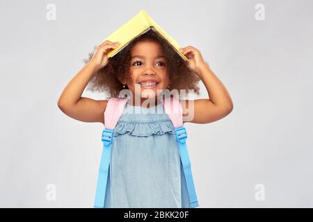 Happy Little african Mädchen mit Buch und Rucksack Stockfoto