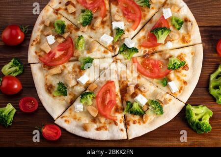 Pizza mit Hähnchen, Brokkoli und Feta-Käse auf Holzhintergrund. Draufsicht. Stockfoto