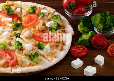 Pizza mit Hähnchen, Brokkoli und Feta-Käse auf Holzhintergrund. Stockfoto