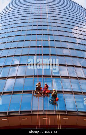 Drei Männer Arbeiter in roten und dunklen Arbeitskleidung reinigen das Äußere Stockfoto