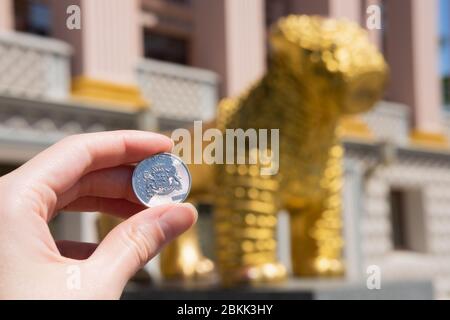 BATUMI, GEORGIEN, Adjara - 4. Mai 2020 Georgische Lari-Münze auf dem Hintergrund eines goldenen Löwen - ein nationales Symbol in Georgien. Hand hält Geld in einem Touristen Stockfoto