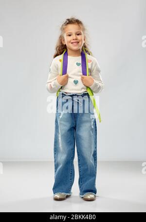 Glückliches kleines Mädchen mit Schulrucksack Stockfoto