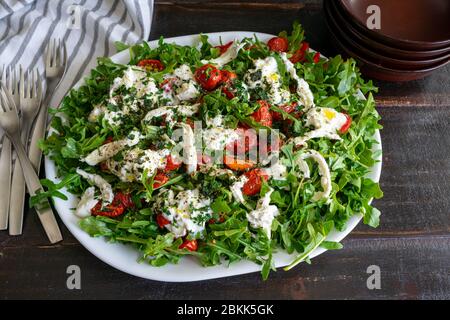 Rucola mit langsam gerösteten Tomaten und Burrata: Eine andere Version des klassischen Caprese-Salats aus Traubentomaten, Rucola, Basilikum und Mozzarella Stockfoto