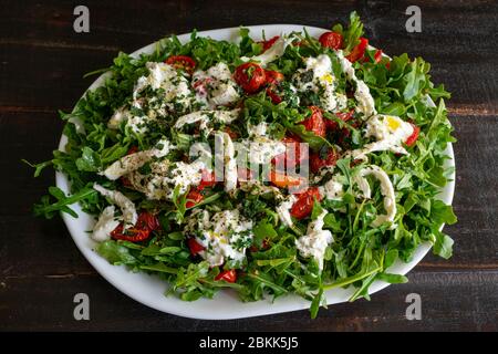 Rucola mit langsam gerösteten Tomaten und Burrata: Eine andere Version des klassischen Caprese-Salats aus Traubentomaten, Rucola, Basilikum und Mozzarella Stockfoto