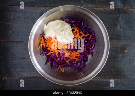 Coleslaw Zutaten in einer Schüssel: Mayonnaise, geschredderter Kohl, Karotten und andere slaw Zutaten Stockfoto