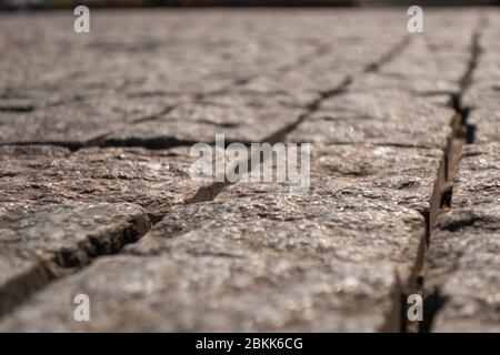Die Struktur der Pflastersteine besteht aus quadratischen Elementen aus Granit in grau und rot. Selektiver Fokus. Die Perspektive ist linear. Stockfoto