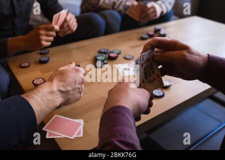 Mehrere Männer spielen Poker in einem Café und halten Karten in ihren Händen Stockfoto
