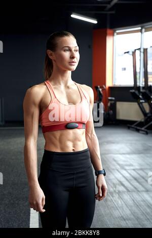 Sportlicher Lifestyle. Junge Frau im Fitnessstudio stehend, die neben nachdenklich schaut Stockfoto
