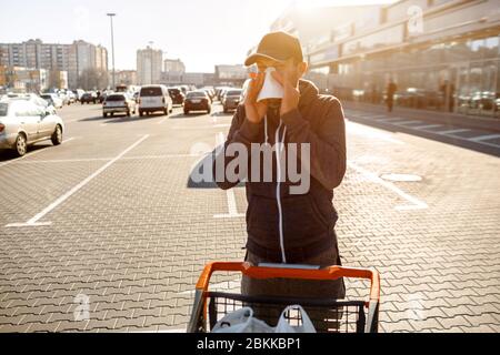 Mann mit Taschentuch. Kranke Mädchen hat laufende Nase. Männlich Modell macht ein Heilmittel für die gemeinsame Kälte i auf Parkplatz Mall Hintergrund Stockfoto