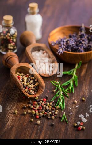 Stillleben mit Salz, Pfeffer, frischer Rosmarin und Lavendel auf Holzhintergrund Stockfoto