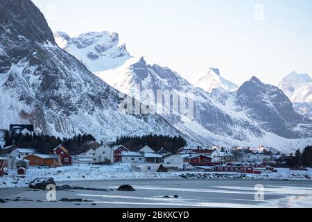 Traditionelle norwegische Holzhaus rorbu am Ufer auf den Fjord und die Berge in der Ferne zu stehen. Lofoten. Norwegen. World Travel Stockfoto