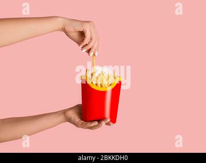 KHARKIV, UKRAINE - 4. APRIL 2020: Junges Mädchen, das eine Packung pommes von McDonald's auf rosa Hintergrund hält Stockfoto