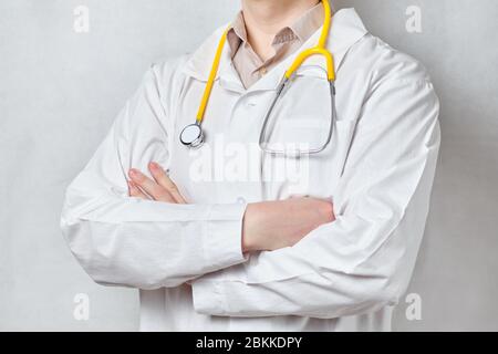 Der Arzt in einem weißen Mantel faltete seine Hände mit einem Stethoskop auf weißem Hintergrund. Nahaufnahme. Stockfoto