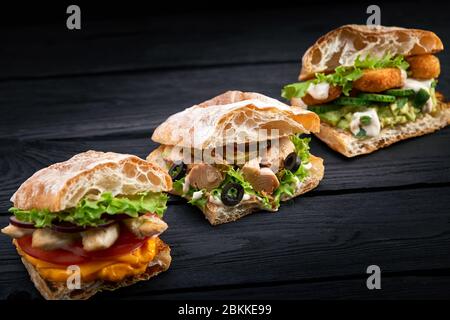 Nahaufnahme drei verschiedene appetitliche Sandwiches oder Burger auf Holz Hintergrund Stockfoto