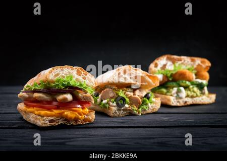 Nahaufnahme drei verschiedene appetitliche Sandwiches oder Burger auf Holz Hintergrund Stockfoto