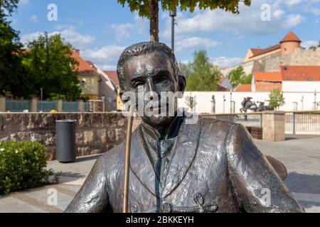 Eger, Ungarn - 04 26 2020: Statue von Geza Gardonyi in Eger, Ungarn mit der Burg im Hintergrund an einem Frühlingsnachmittag. Stockfoto