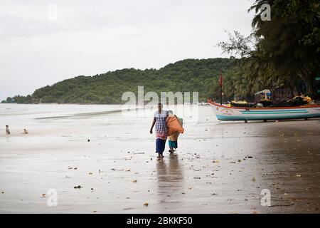 Nach heftigem Regen am Strand in Goa, Indien, gehen Frauen auf Boote für fis Stockfoto