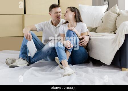 Glückliches Paar sitzt in der Nähe von Kisten in einer neuen Wohnung Stockfoto