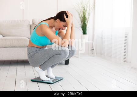 Frau Weint Auf Der Waage Zu Hause An Gewicht Gewinnen Stockfoto