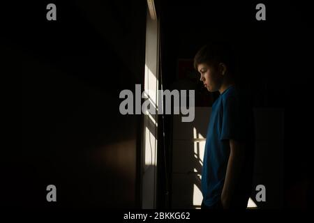 Junge teen junge Blick aus dem Fenster während der Isolation Stockfoto