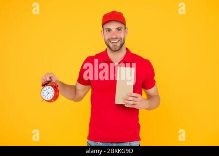 Echte Freude. Gehen Sie online einkaufen. Lieferung während der Quarantäne. Freundliche Mitarbeiter Mann. Lieferzeit. Lieferung Kurier mit Zeit Uhr Haltekasten. Nehmen Sie Ihr Paket. Geschenk Lieferung Mann mit Vintage Uhr. Stockfoto