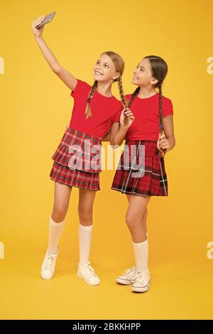 Familie Abbinden. Schwesternschaft und Freundschaft. Glücklich wissen Tag. Kindheit Glück. Bildung Konzept. zurück zu Schule. sozialen Netzwerk. Mädchen in Uniform. kleine Mädchen selfie am Telefon machen. Spaß haben. Stockfoto