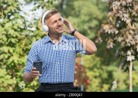 Vorteile für Remote-Arbeit. Kaffeepause. Belohnen Sie sich und ermutigen. Mann trinkt Kaffee hören Lieblingsmusik Künstler. Mittagszeit. Kaffee im Freien Natur Hintergrund. Inspiriert von der Umwelt. Stockfoto