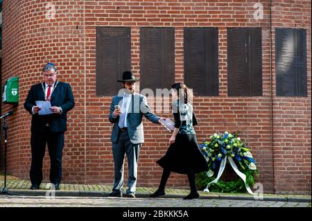Ein Mädchen aus Juden wird gesehen, wie es Rabbi M. Levin während der Zeremonie ein Buch überreicht.die gedenkfeier fand in der "Kitty de Wijze" statt, einem Denkmal, das zum Symbol der Juden in Nijmegen wurde, die deportiert wurden und nie wieder zurückkamen. In diesem Jahr wurde die Zeremonie aufgrund der aktuellen Situation ohne Zuhörerschaft abgehalten, nur in Anwesenheit von Rabbi M. Levin und Bürgermeister von Nijmegen Hubert Pinselwood ist auch Vorsitzender des Sicherheitsrates des Landes. Der Gedenkgottesdienst in der Sint Stevens Kirche wurde in diesem Jahr abgesagt. Stockfoto