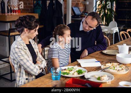 Junge Eltern helfen ihrer Tochter, einen Brief an jemanden zu schreiben. Stockfoto