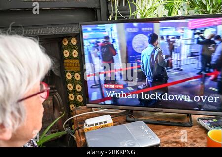 Eine Frau, die BBC Nachrichten mit Entwicklungen in Wuhan, China betreffend Covid-19 mit der Überschrift 'Wuhan Lockdown over' beobachtet. Stockfoto