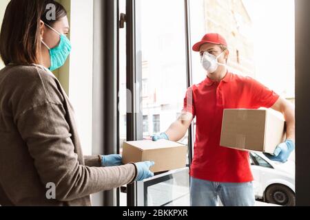 Frau erhält Paket von Kurier in Maske Stockfoto