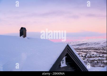 Sonnenuntergangsbild von Hovden Norwegen mit Dach eines Hauses mit Schnee bedeckt Stockfoto