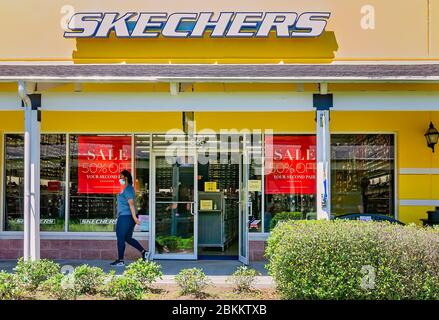 Eine Frau mit Gesichtsmaske geht an Skechers vorbei in Gulfport Premium Outlets, 1. Mai 2020, in Gulfport, Mississippi. Geschäfte am Outlet geschlossen Mitte Stockfoto