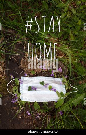 Blaue Schutzmaske mit Frühlingsblumen verziert, bleiben Isolation zu Hause für die Selbstquarantäne. Konzept Home Quarantäne, Prävention COVID-19, Coronavi Stockfoto