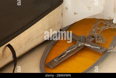 Nahaufnahme zeigt großes Kruzifix auf Kette mit Gold Glasmalereien Hintergrund neben einer geschlossenen Bibel mit weißem Stern Hintergrund Indicativ für den Himmel. Stockfoto