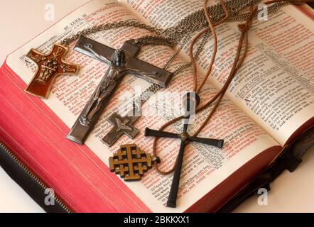 Viele Kreuze auf einer offenen roten Buchstaben Bibel angezeigt. Kreuze sind Halsbekleidung mit Jesus, Taube, Brote und Fische, oder Jerusalem. Stockfoto