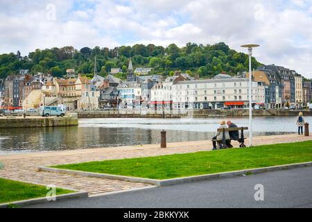 Ein älteres Rentnerpaar sitzt auf einer Parkbank und genießt an einem teilweise bewölkten Nachmittag den Blick auf das Fischerdorf Honfleur France in der Normandie Stockfoto