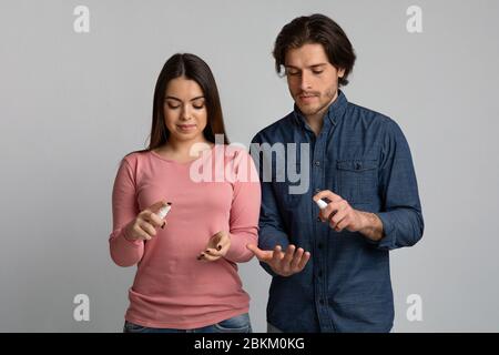 Vorsichtsmaßnahmen Während Des Ausbruch Des Coronavirus. Junges Paar Anwendung Desinfektionsmittel Spray auf die Hände Stockfoto