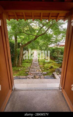 Der Blick durch den Rahmen des alten Holztores auf den Garten mit der Steinstraße. Ryoan-ji-Tempel. Kyoto.Japan Stockfoto