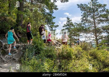 Altai Republik, Russland - 2019, Menschen gehen auf einem Weg in einem Sommer bergigen Wald, selektive Fokus Stockfoto