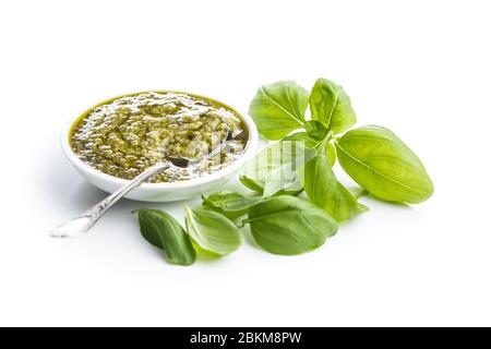 Grüne Basilikumpesto-Dip-Sauce und Basilikumblätter auf weißem Hintergrund isoliert. Stockfoto