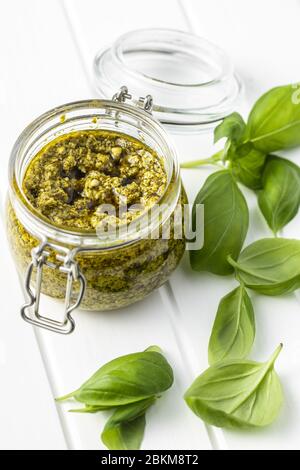 Grüne Basilikumpesto-Dip-Sauce im Glas und Basilikumblättern. Stockfoto