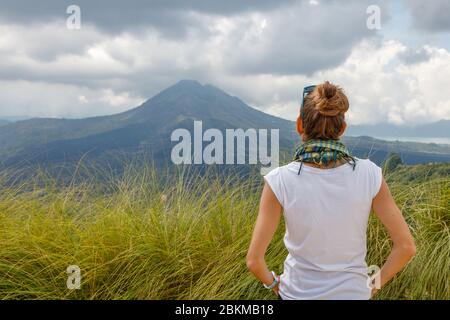 Eine Frau, die den Blick auf den Vulkan Batur (Gunung Batur) und den Batur-See (Danau Batur) beobachtet. Kintamani, Bangli, Bali, Indonesien. Stockfoto