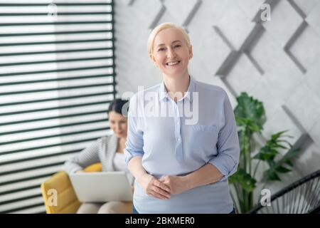 Erwachsene lächelnde blonde Frau im Zimmer stehen. Stockfoto