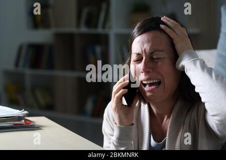 Traurige Erwachsene Frau ruft am Smartphone weinend auf dem Boden in der Nacht zu Hause sitzen Stockfoto