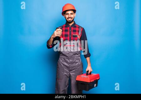 Porträt des indischen glücklichen Mannes mit einer roten Werkzeugkiste isoliert auf blauem Hintergrund Stockfoto